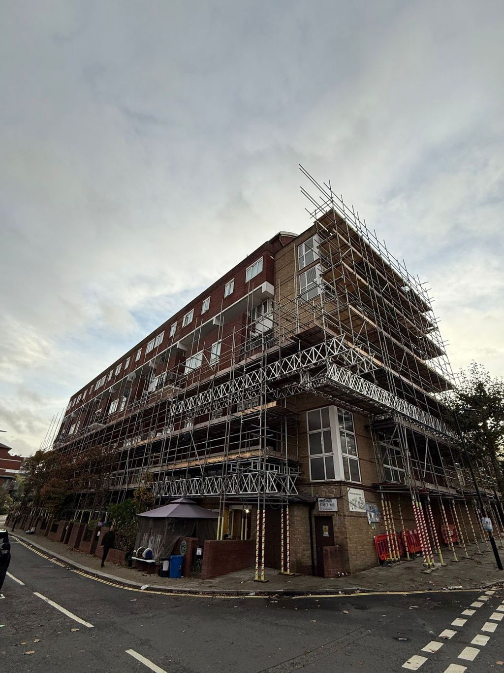 Return scaffold with cantilevered loading bays on a corner block above a live road