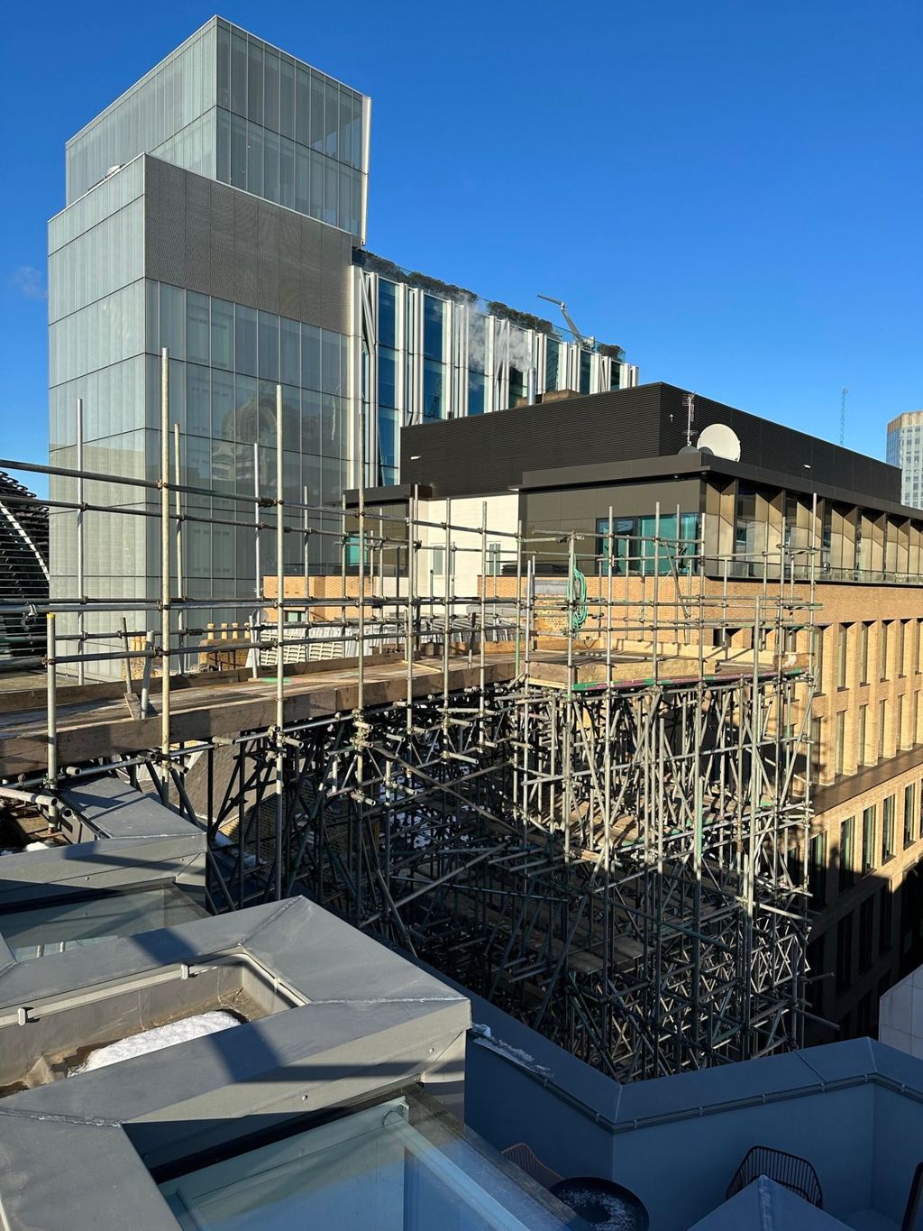 High-level commercial roofing scaffold with birdcage detail over an occupied building